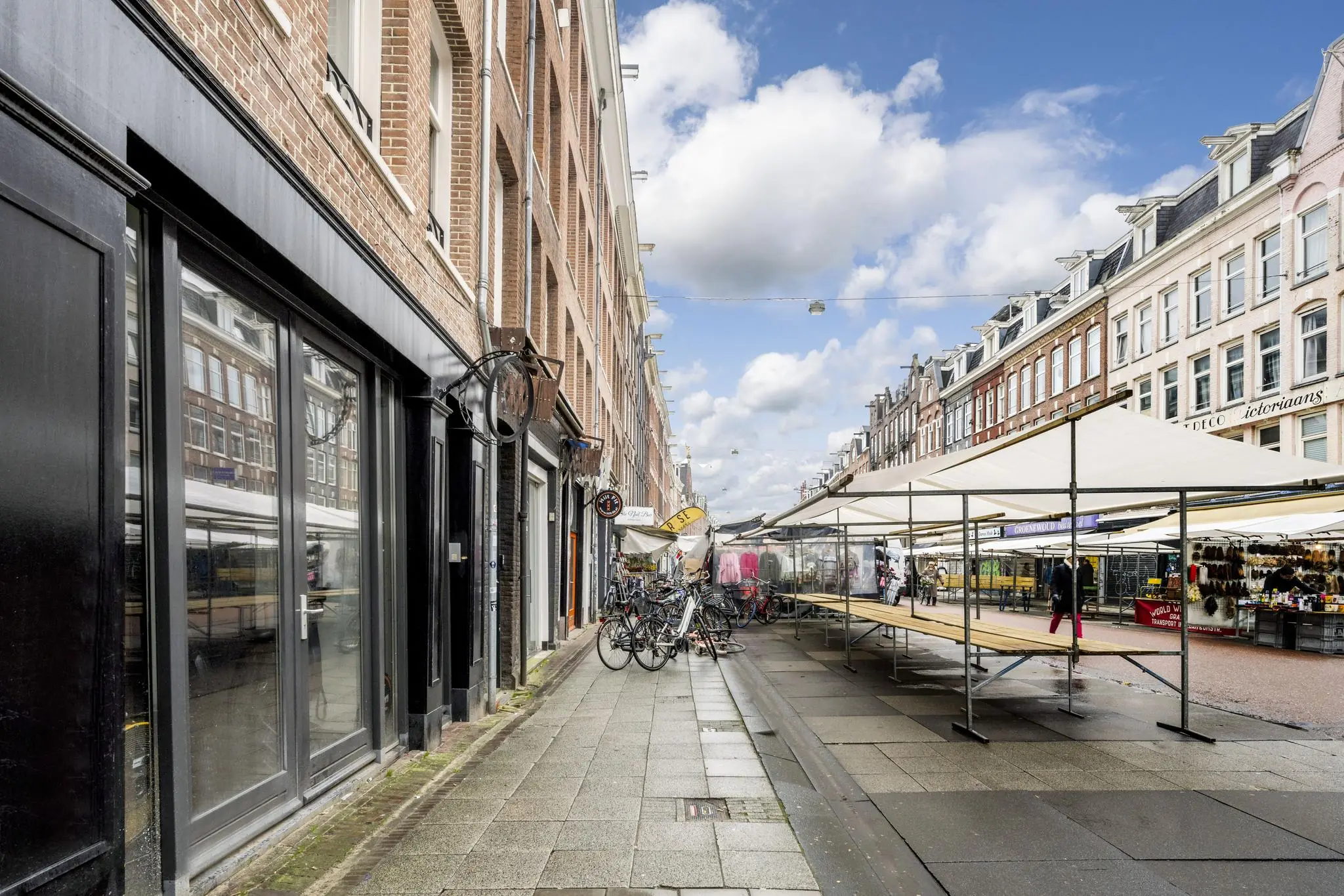 Marktkramen en winkels aan de Albert Cuypstraat in Amsterdam op een deels bewolkte dag.